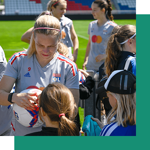 Joueuse de l'OL féminin signe un ballon lors d'un entrainement privé dédié à de jeunes footballeuses